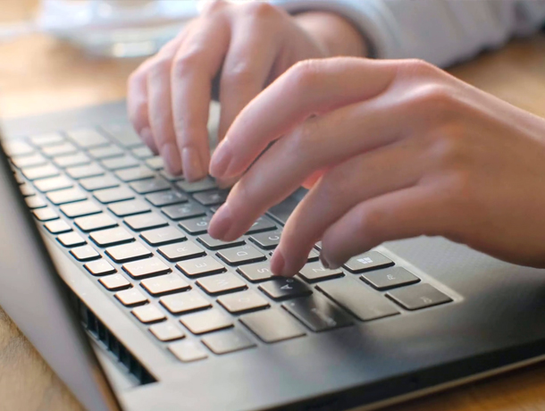 Woman typing on a laptop with hot cocoa to the side